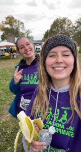 Two smiling BIFSTL runners pose with a peace sign and a banana at the Stampede for Stroke run